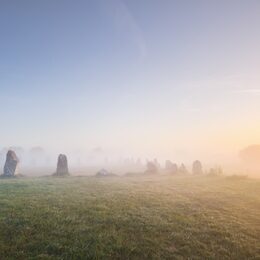 Menhir alignment view at Camaret sur mer in a morning fog at sunrise. Brittany, France. Golden light. Panoramic picturesque scenery. Travel destinations, national landmarks. sightseeing, history
