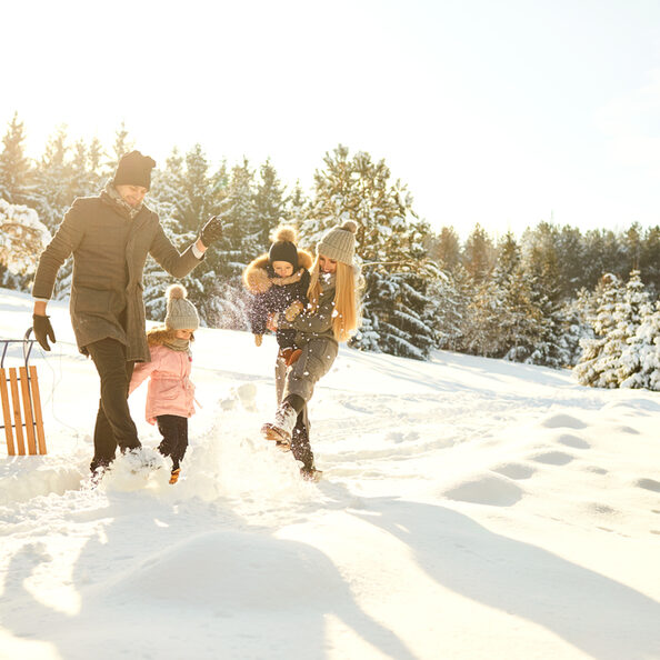 Playful couple with kids in winter woods