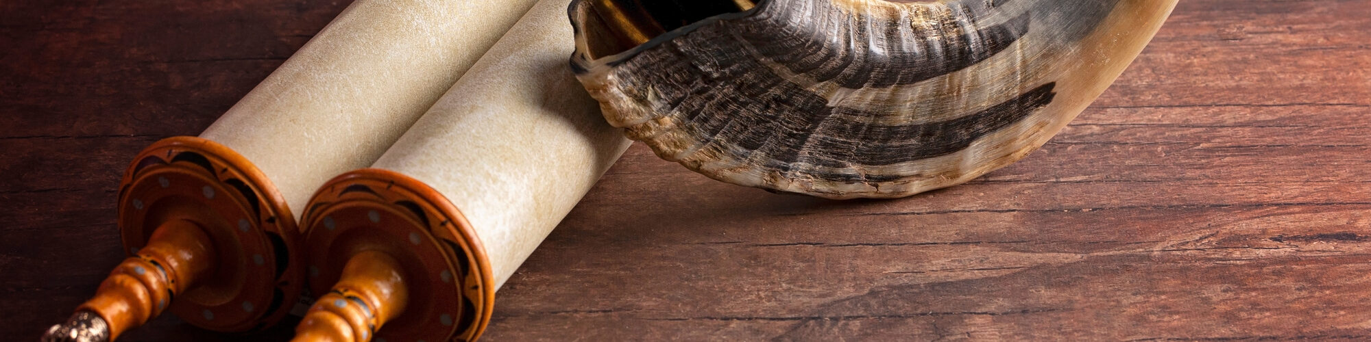 A Shofar Rams Horn and a Tora Scroll on a Wooden Table